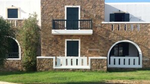 A two-story building with a stone facade, white railings, and a balcony. - Plaka Hotel I (Naxos)