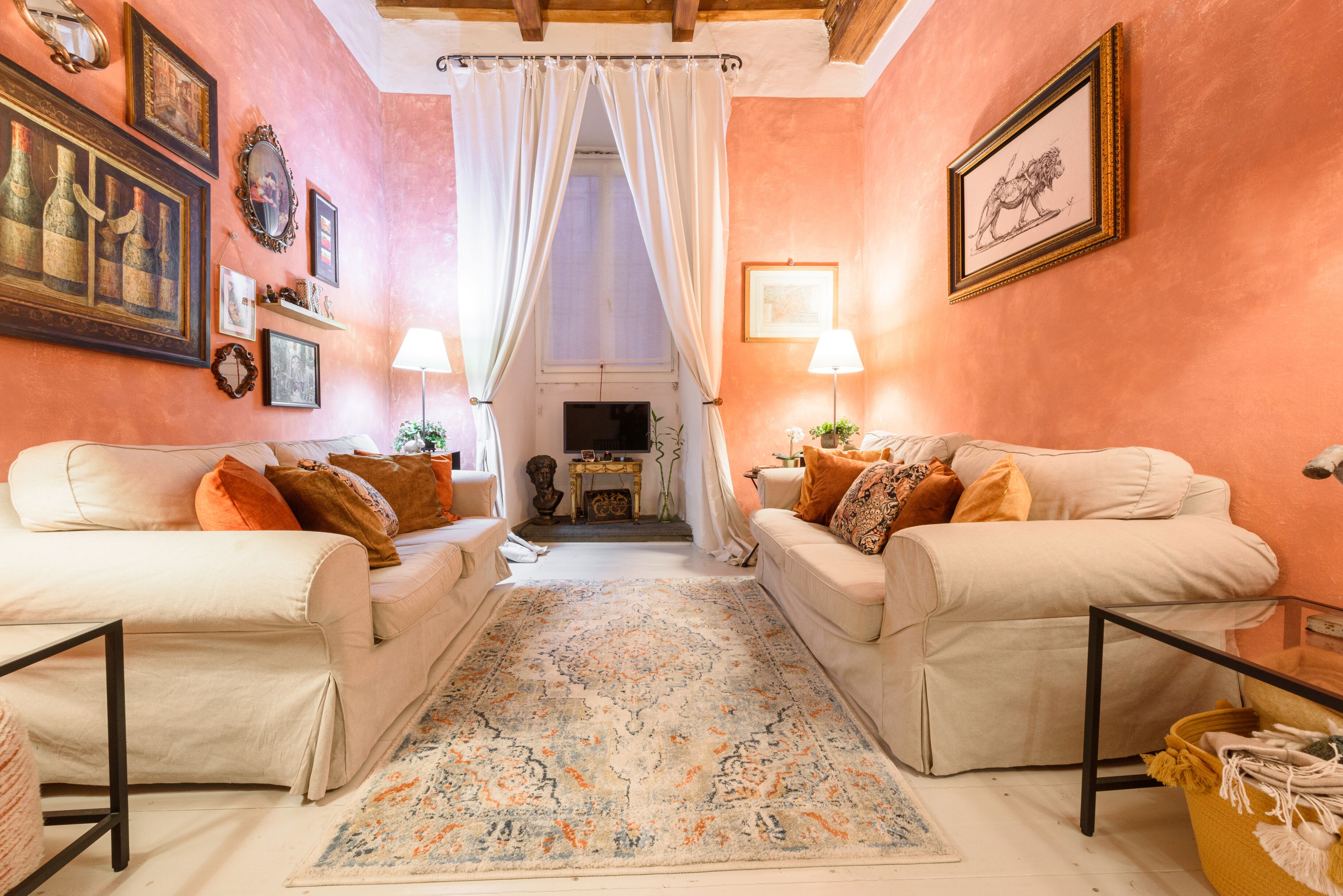 Ein gemütliches Wohnzimmer mit zwei weißen Sofas, einem gemusterten Teppich und einem Kamin.