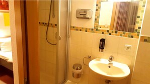 A bathroom with a shower, sink, and a mirror. - Gasthof Franziska (Stuttgart)