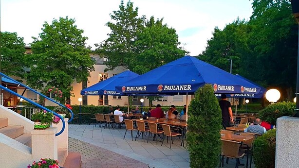 An outdoor seating area with tables and chairs under blue umbrellas, a staircase, and potted plants. - Gasthof Franziska (Stuttgart)
