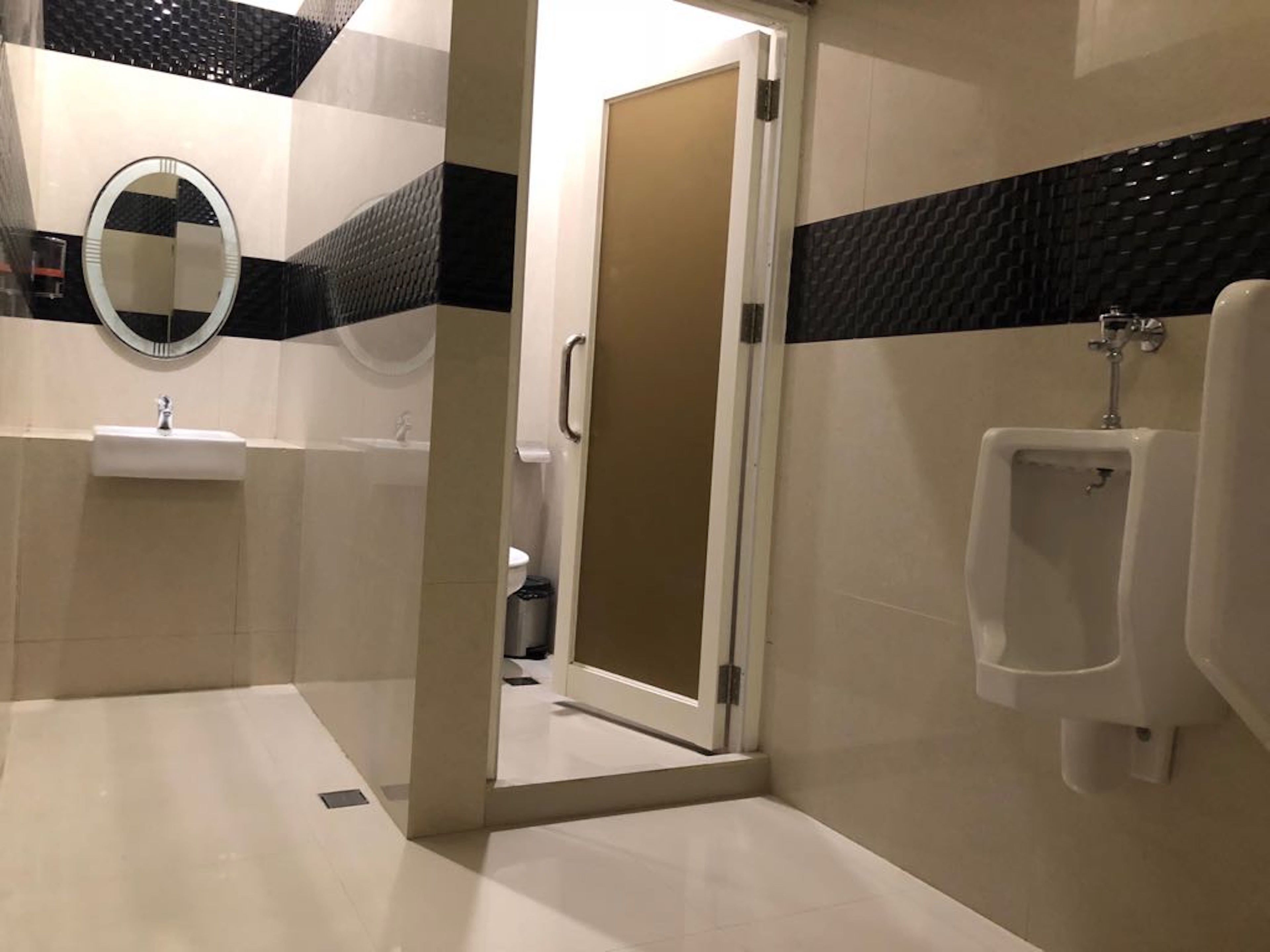 A modern bathroom with a glass-enclosed shower, a sink, and a urinal.