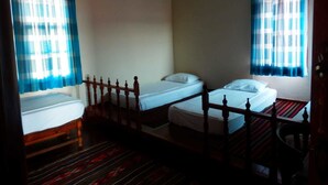 A room with three single beds, wooden headboards, and a patterned carpet. - Taksiyarhis Pension (Ayvalik)