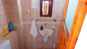 A small bathroom with a toilet, sink, and mirror. - Taksiyarhis Pension (Ayvalik)