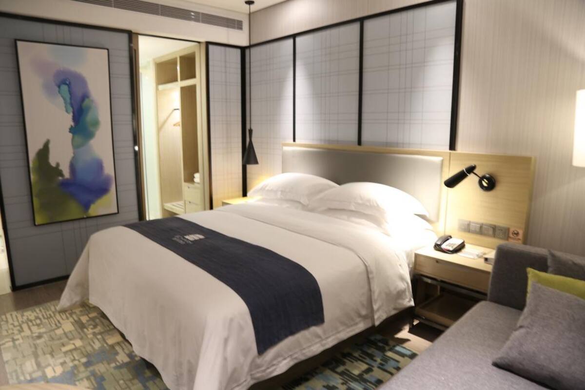 A hotel room with a large bed, bedside table, and a desk.