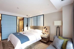A modern hotel room with a large bed, bedside tables, a lamp, and a sofa. - Echarm Hotel Kecun Pazhou (Guangzhou)
