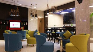 A modern lobby with blue and yellow seating, a TV screen, and pendant lighting. - Echarm Hotel Kecun Pazhou (Guangzhou)