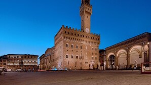 A historic building with a prominent tower and arched windows, situated in a spacious square. - Tiny Ponte Vecchio by Mmega (Florence)