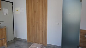 A room with a wooden wardrobe, a blue door, and a tiled floor. - Hostal Usera (Madrid)