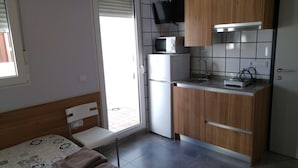 A compact kitchen with a microwave, sink, and wooden cabinets. - Hostal Usera (Madrid)