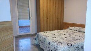 A bedroom with a bed, a wooden wardrobe, and a sliding glass door leading to a balcony. - Hostal Usera (Madrid)