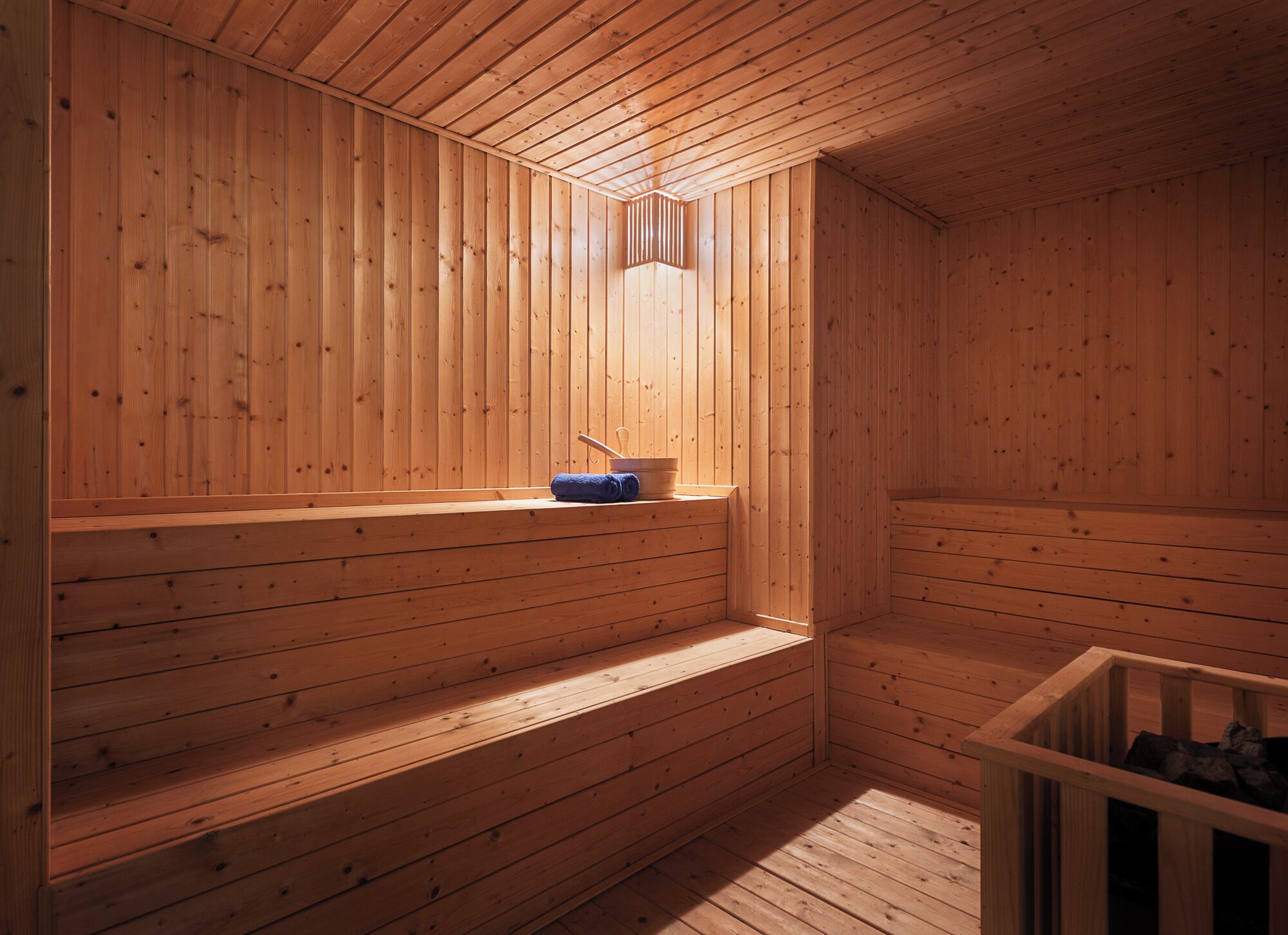 Una sauna de madera con bancos y una pequeña ventana.