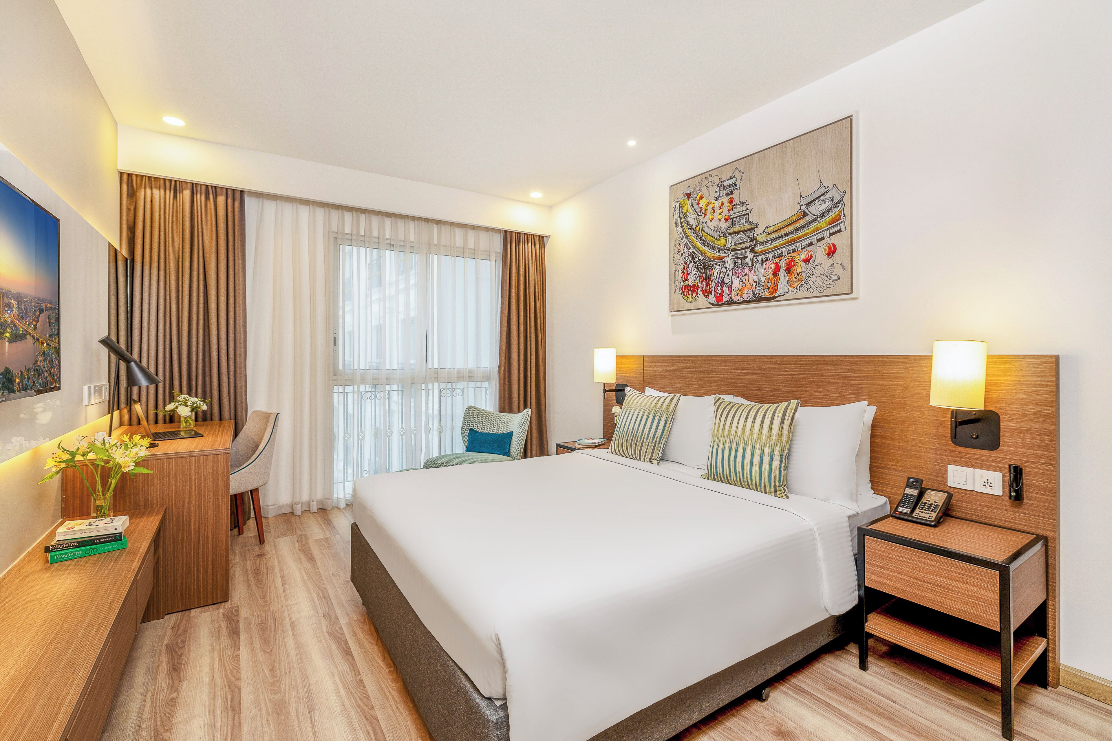 A hotel room with a large bed, a desk with a chair, a nightstand, and a painting on the wall.