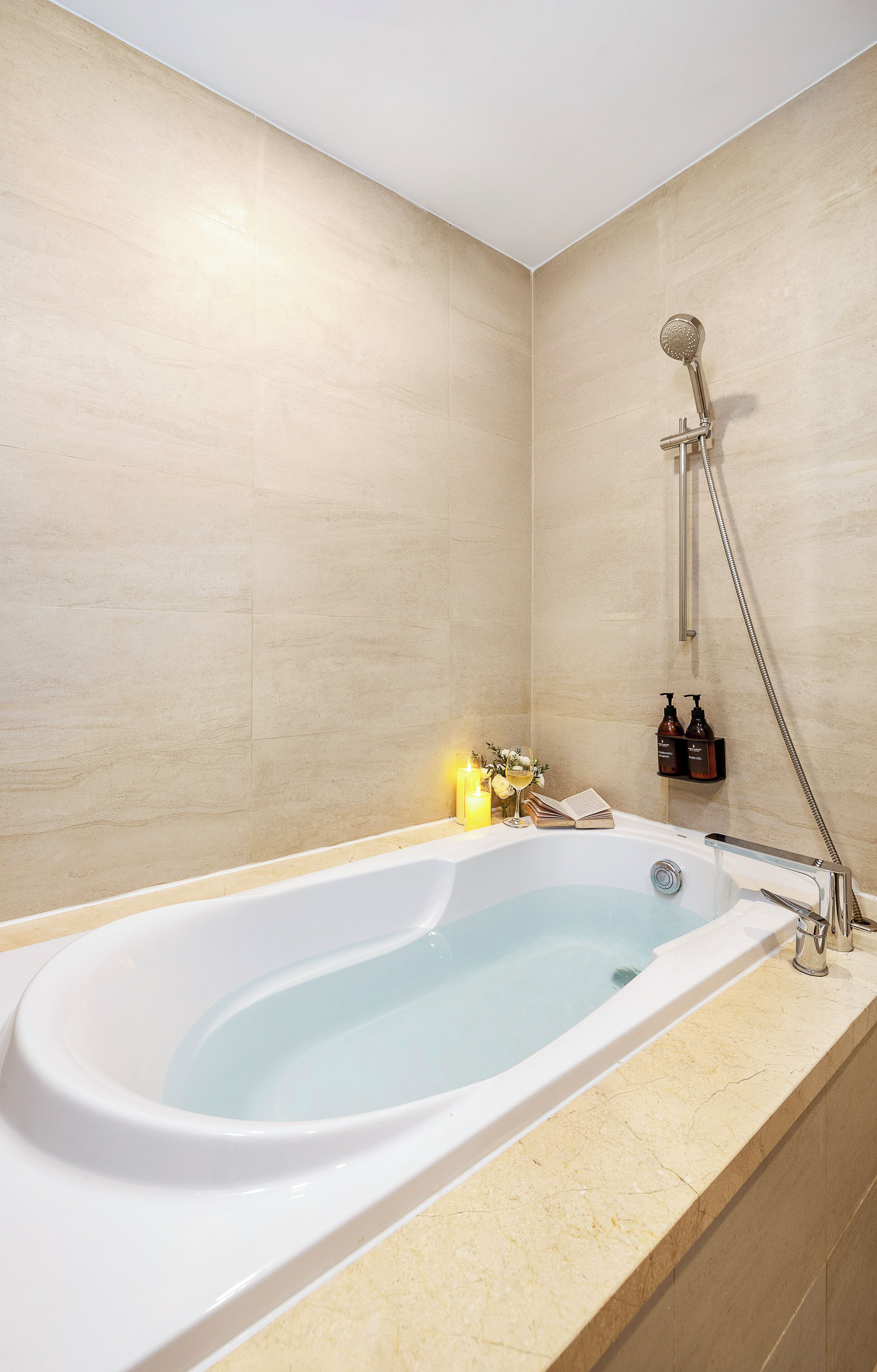 Un baño moderno con una bañera independiente, un cabezal de ducha de mano y un estante pequeño con artículos de aseo.