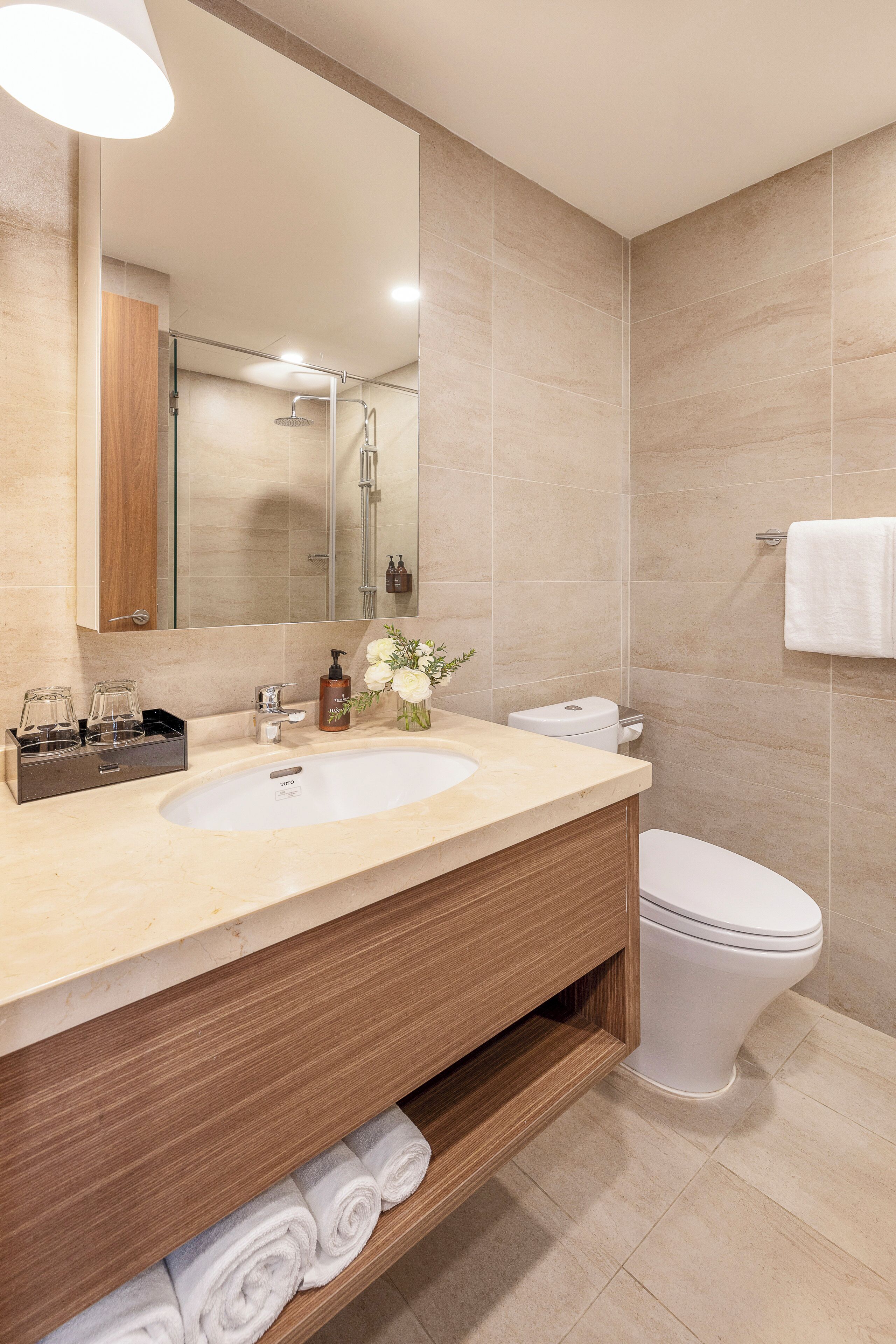 A modern bathroom with a large mirror, two sinks, a toilet, and a shower.