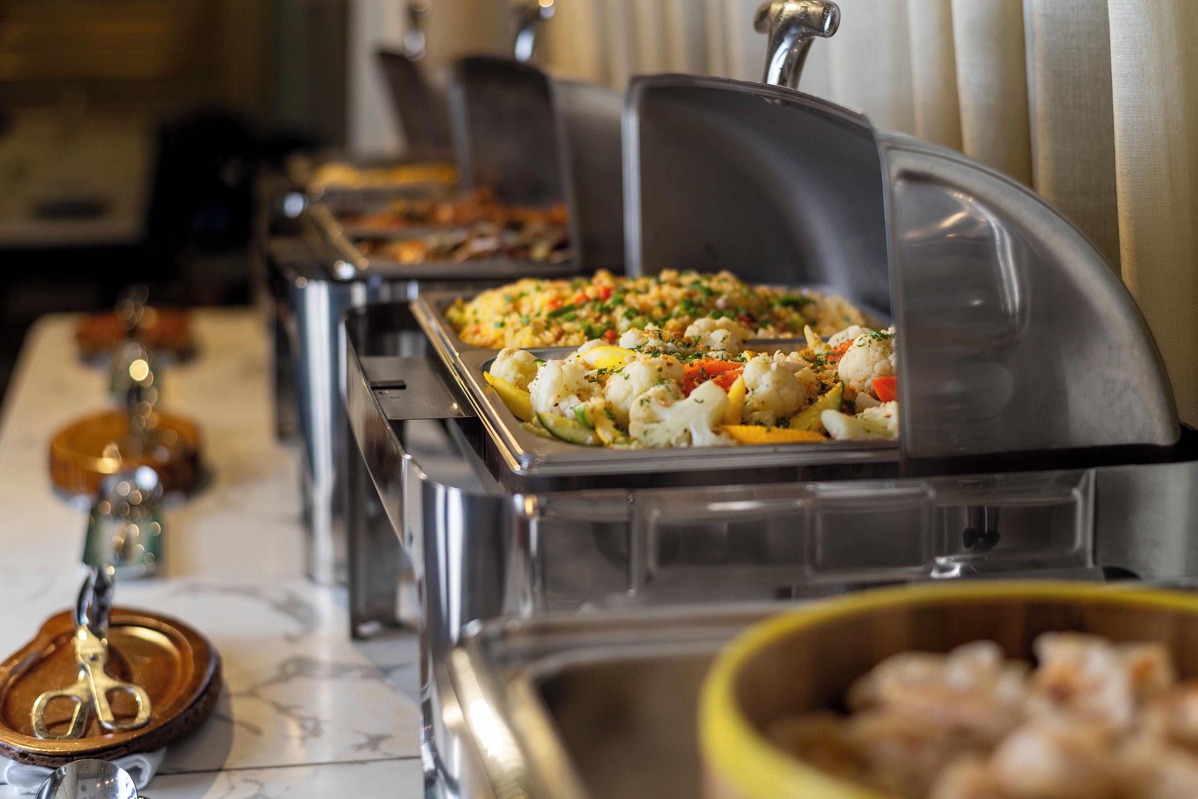 A buffet with various dishes, including a salad with vegetables and a dish with shrimp.