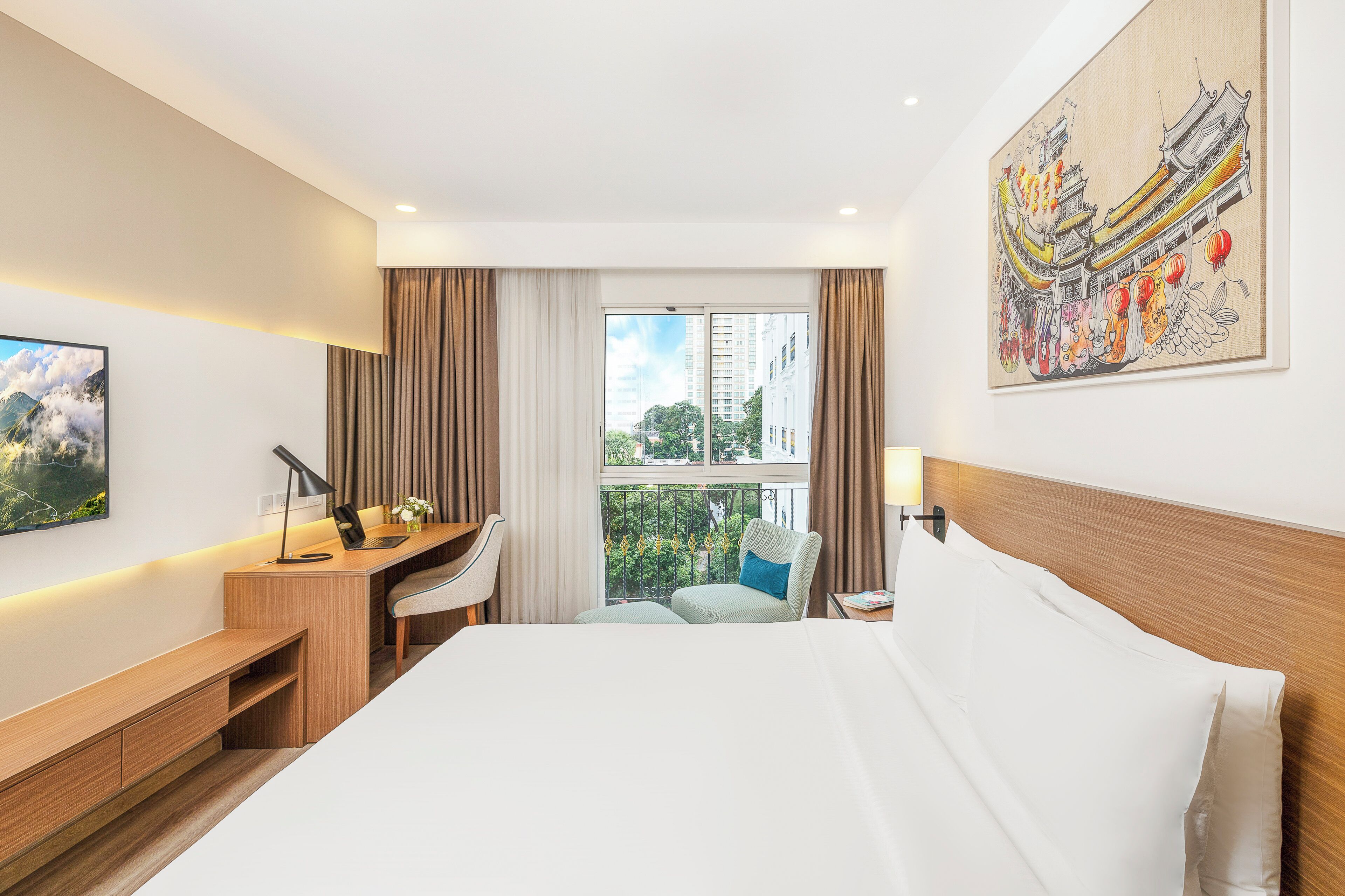 A hotel room with a large bed, a desk, a chair, a laptop, and a painting on the wall.