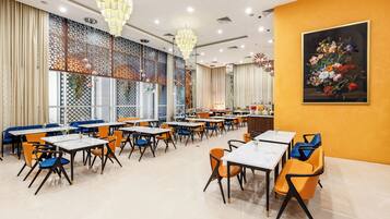 A restaurant with multiple tables and chairs, a decorative wall with a painting, and a patterned window design.