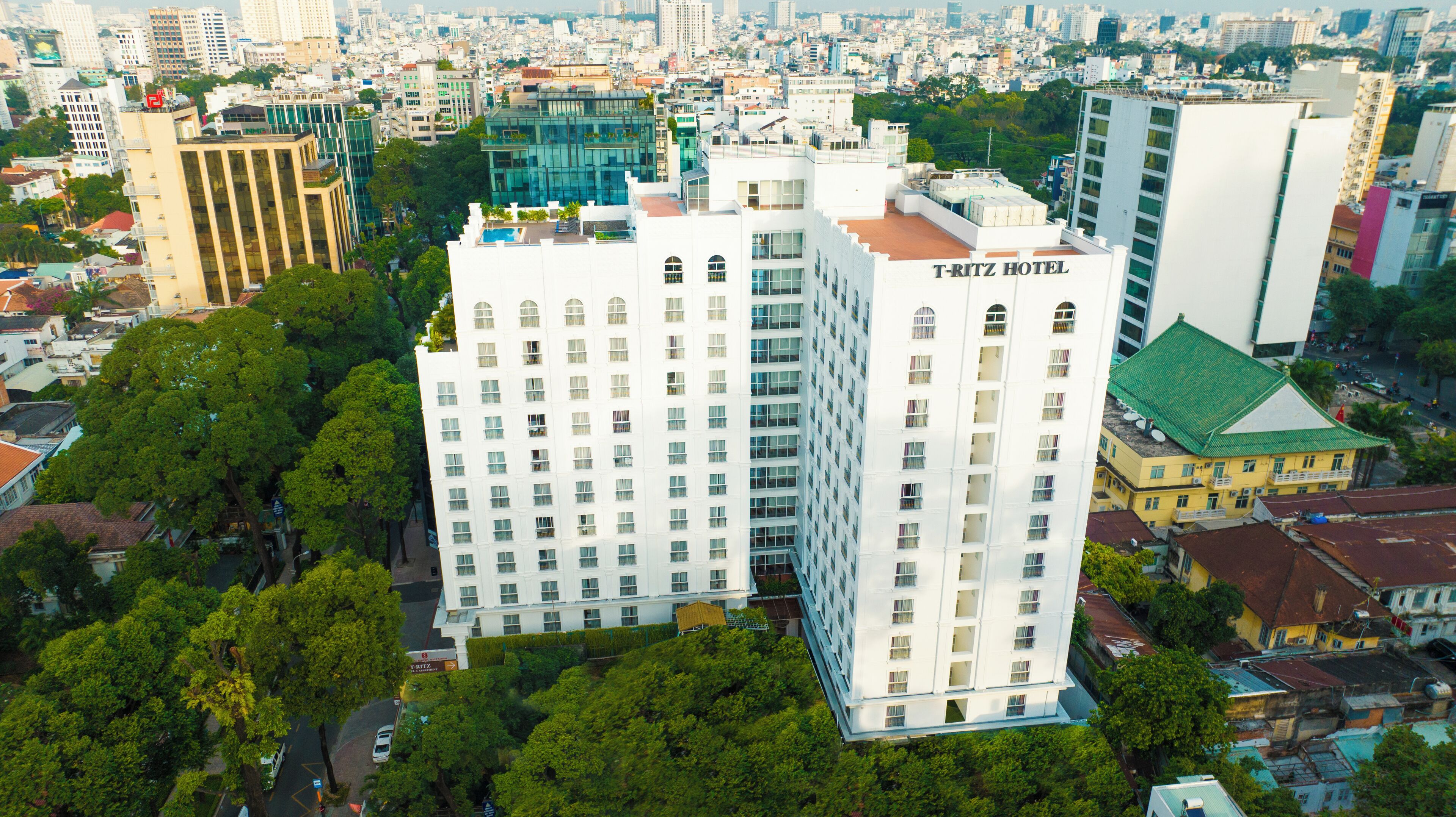 Un hotel de gran altura con varios pisos, rodeado de edificios urbanos y vegetación.