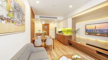 A modern living room with a sofa, dining area, kitchen, and a large painting on the wall.
