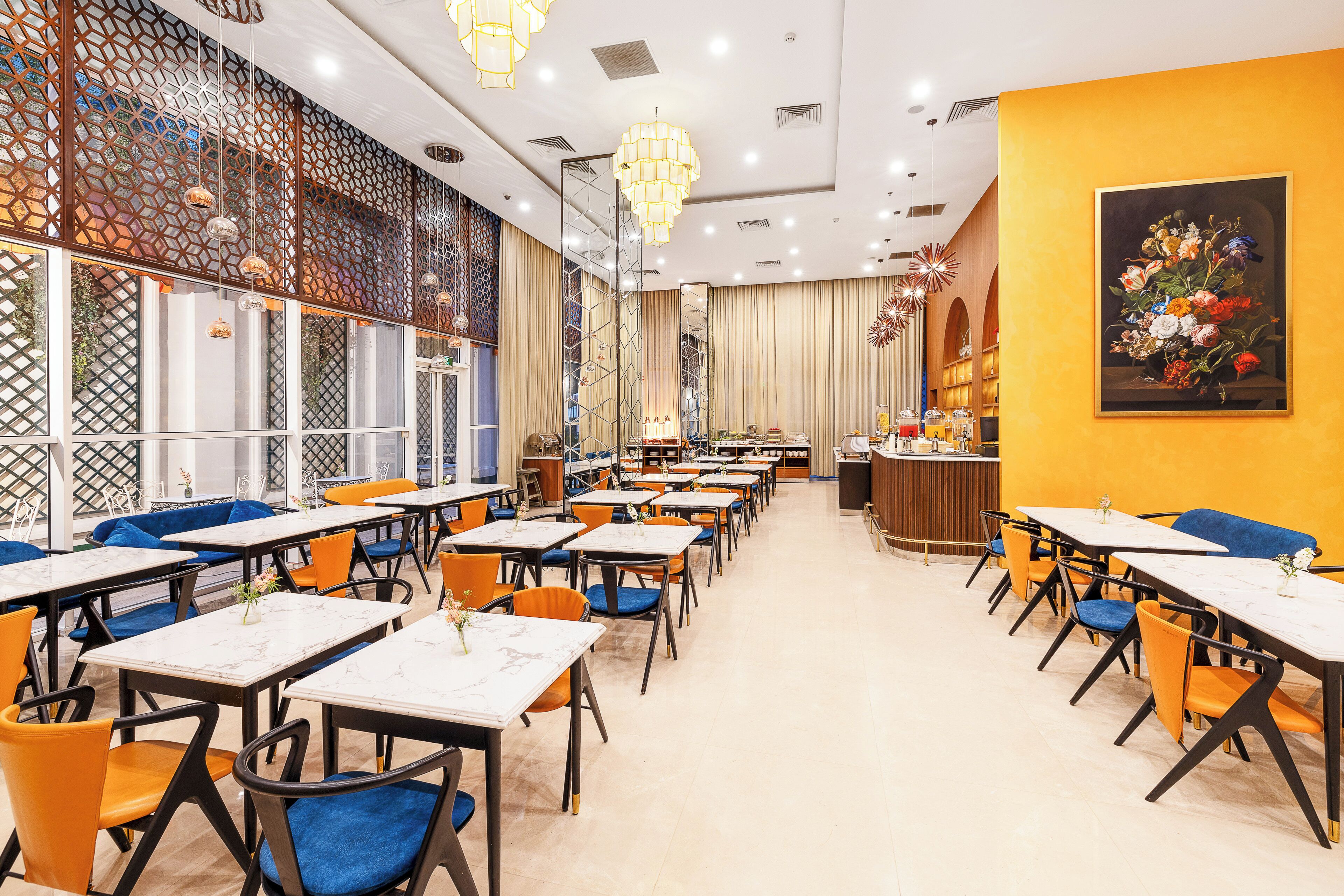 A restaurant with multiple tables and chairs, a decorative wall with a painting, and a bar area.