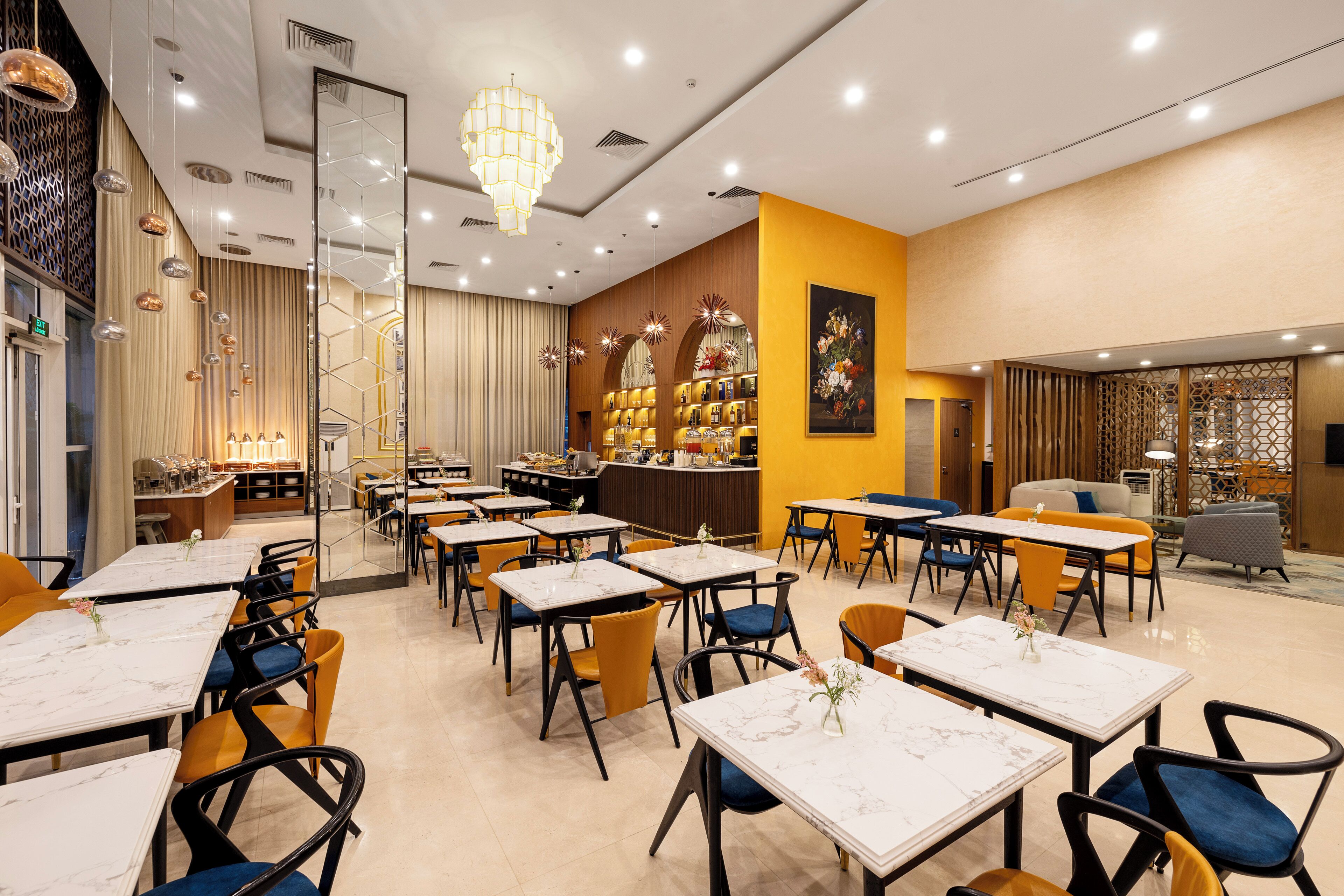 Ein Restaurant mit mehreren Tischen und Stühlen, einer Bar und einer dekorativen Deckenleuchte.