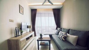 A modern living room with a sofa, a coffee table, a TV on a wooden console, and a ceiling fan. - Merton Residence Ipoh (Ipoh)