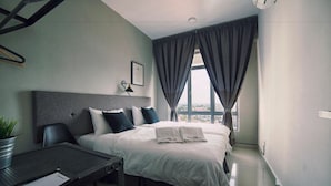 A modern hotel room with a large bed, a desk, and a view of the city through the window. - Merton Residence Ipoh (Ipoh)