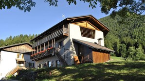 A modern two-story house with a wooden facade, a balcony with red flowers, and a stone staircase leading to the entrance. - Agritur La Gemma (Sant'Orsola Terme)
