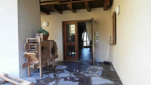 A stone-floored corridor with a wooden bench and a rustic grinder. - Agritur La Gemma (Sant'Orsola Terme)