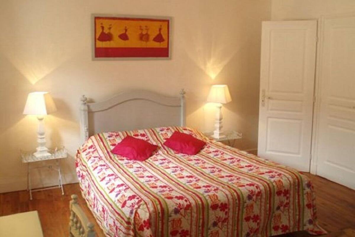 Ein Schlafzimmer mit einem Bett, zwei Nachttischen, einer Lampe, einer Tür und einer Wanddekoration.