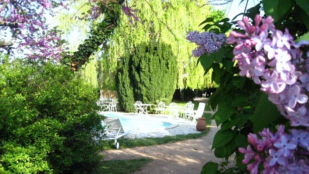 Un jardín con piscina, muebles de exterior blancos y un sendero.