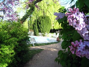 A garden with a pool, white outdoor furniture, and a path. - Chambres d'hôtes Le Calme (Denice)