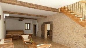Amplia sala de estar con pared de piedra, muebles de madera y una escalera de madera.