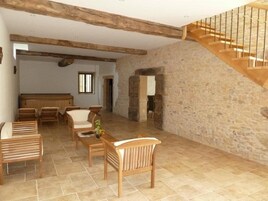 Amplia sala de estar con pared de piedra, muebles de madera y una escalera de madera.