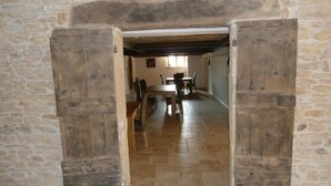 Una habitación con paredes de piedra y una rústica puerta de madera que da a un comedor con una mesa y sillas.