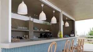 A bar area with a blue tiled backsplash, wooden chairs, and pendant lights. - Maggana Residence (Kefalonia)