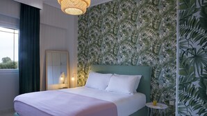 A bedroom with a large bed, a nightstand, a mirror, and a tropical leaf-patterned wall. - Maggana Residence (Kefalonia)