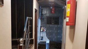 Um corredor estreito com uma escada à esquerda e uma área de cozinha à direita.