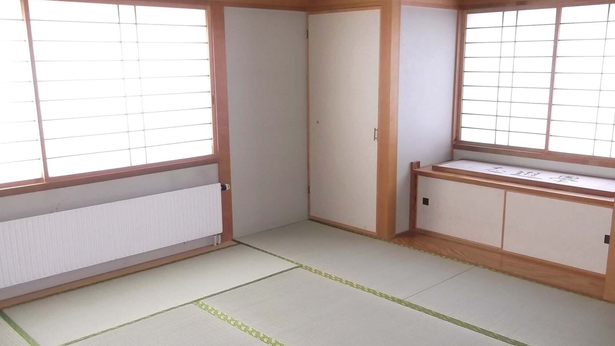 Ett traditionellt japanskt rum med tatamimattor på golvet, skjutdörrar och ett lågt träbord.