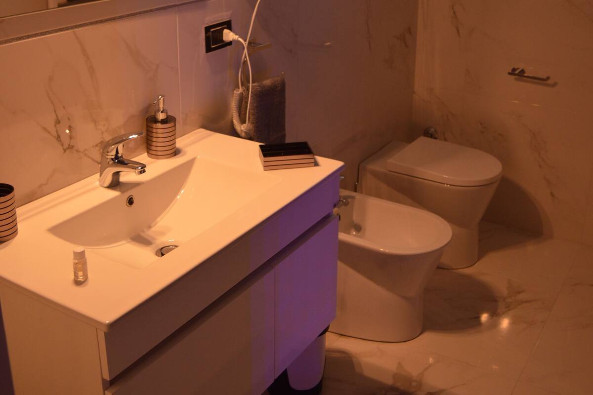 A bathroom with a white sink, mirror, and a white toilet.