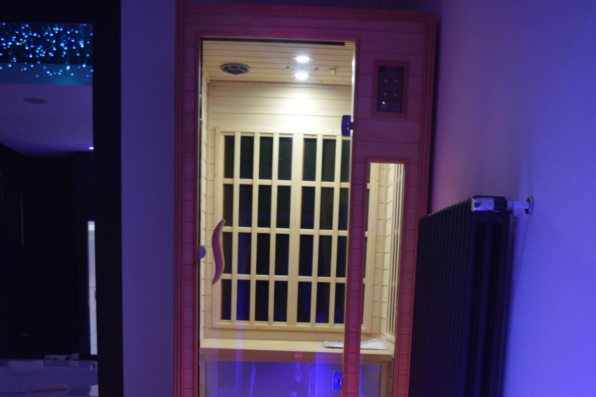 A wooden door with a glass panel and a metal gate, leading to a room with a tiled floor and a radiator.