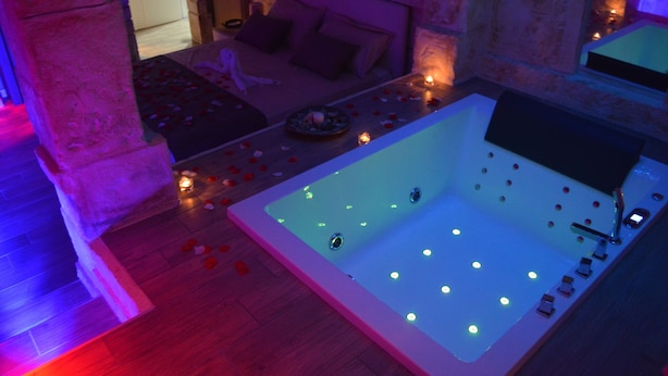 Une salle de bain moderne avec une grande baignoire, un mur en pierre et un plancher en bois.