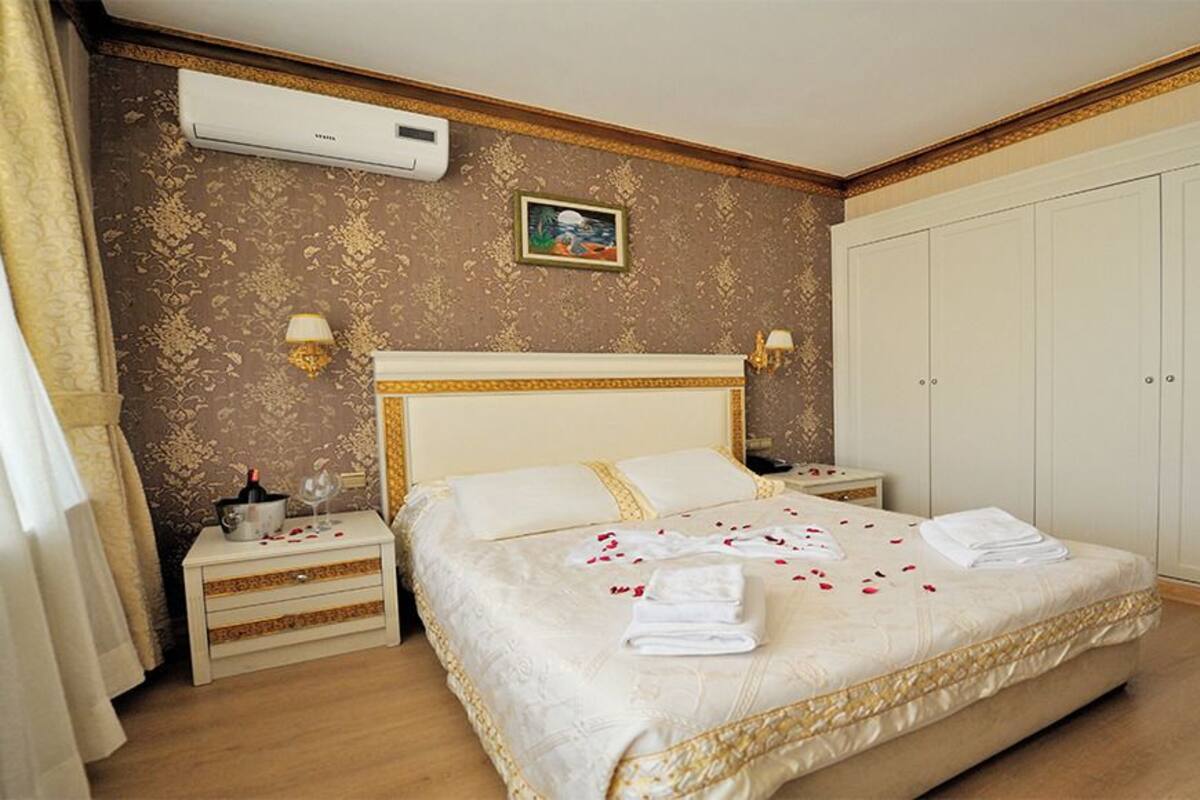 Quarto de hotel com uma cama grande, um guarda-roupa, uma mesa de cabeceira e um aparelho de ar condicionado.