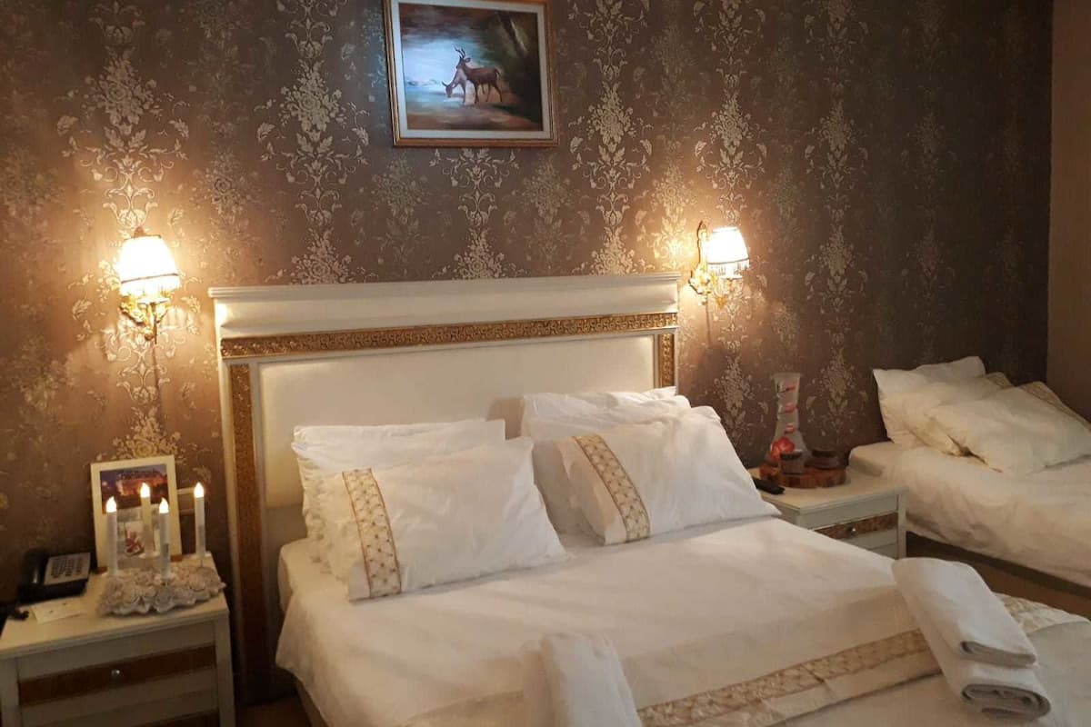 Quarto de hotel com uma cama grande, duas mesas de cabeceira e um quadro na parede.