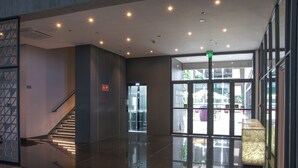 A modern lobby with a glass entrance, a staircase, and a marble reception desk. - Holiday Inn Express Farroupilha by IHG (Farroupilha)