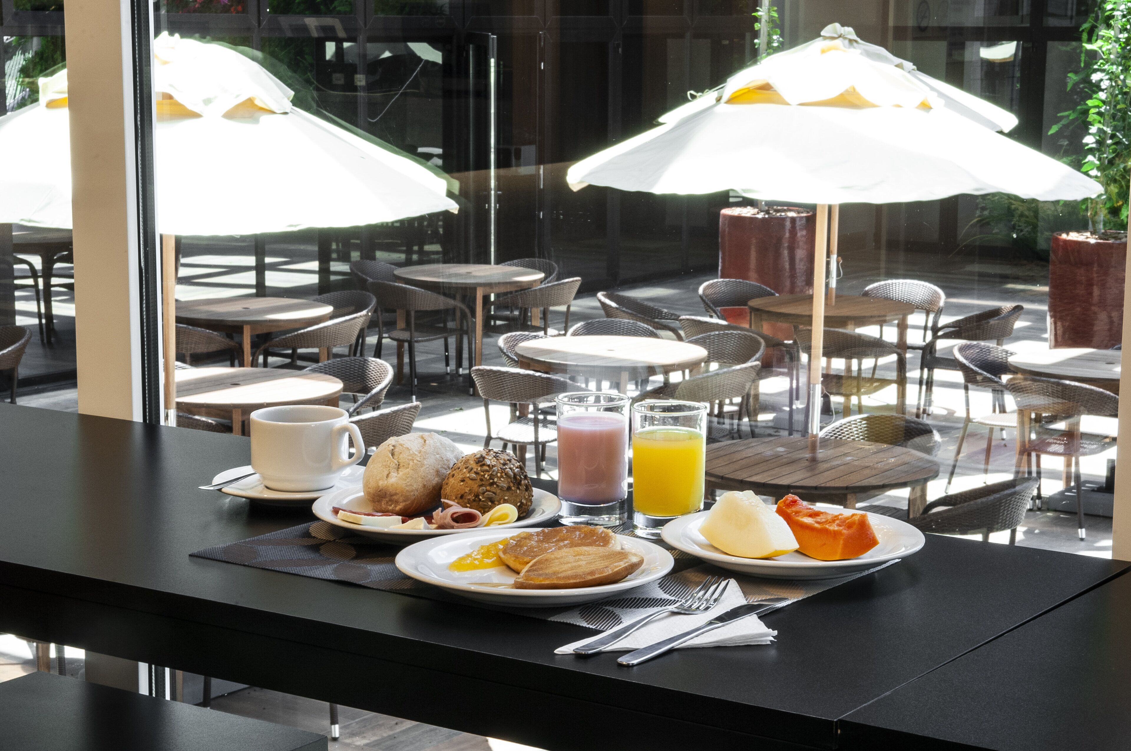 A breakfast setting with a table, chairs, and a view through a window.