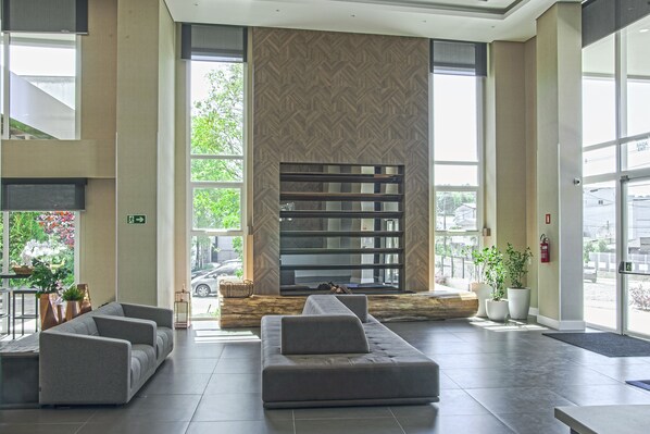 A spacious lobby with a modern sofa, a large bookshelf, and potted plants.