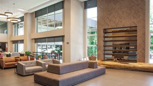 A spacious lobby with a large seating area, high ceilings, and large windows offering views of the outdoors.