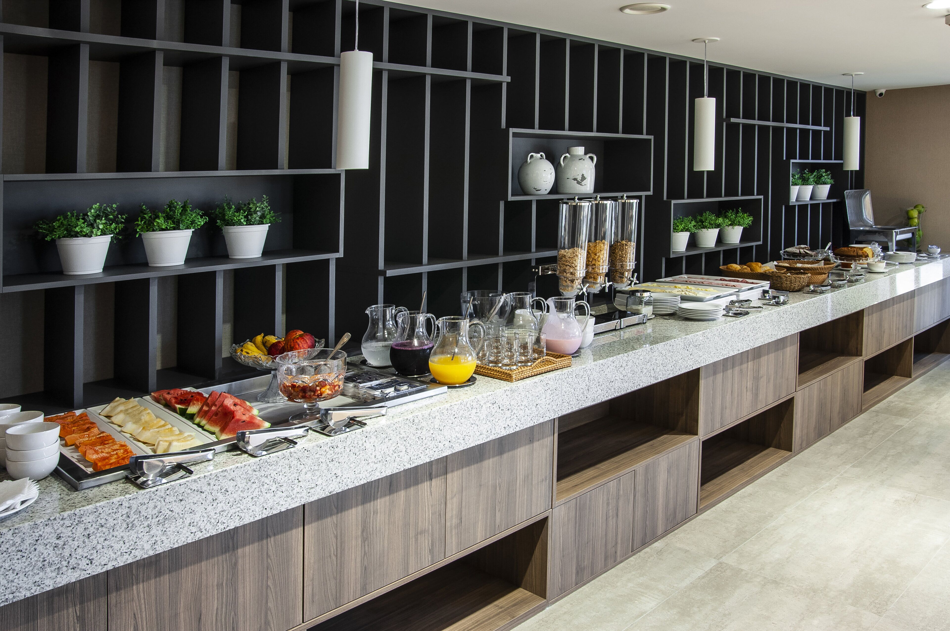 A buffet setup with various food items and drinks, including fruits, cereals, and beverages.