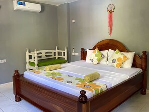 A neatly made bed with floral bedding, a wooden headboard, and a green cushion.